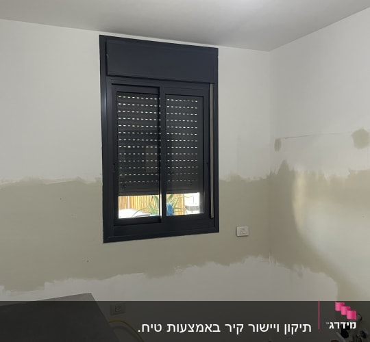 קיר עם חלון ותריסים, חלק מהקיר צבוע בצבע שונה